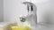 Bathroom cleaning close up. A hand in a protective glove washes a faucet with detergent foam,