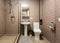 Bathroom covered brown tiled, mirror and sanitary engineering is in the apartment that is afer construction, remodeling