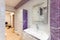 Bathroom covered white-purple tiled, mirror and sanitary engineering is in the apartment that is under construction, remodeling,