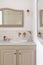 Bathroom decorated in beige color with sinks, golden faucets and vintage mirror. Interior of restroom in retro or