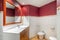 Bathroom decorated in red and white tones with a mirror, bidet, toilet. Clean and empty bathroom