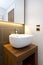 Bathroom detail of a stylish designer hand wash basin with wooden stand