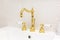 Bathroom faucet made of gold. Antique style. Gold-plated handles with white accents