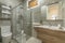 Bathroom with faux marble tile, walk-in shower with sliding glass doors,