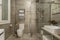 Bathroom with faux marble tile, walk in shower with sliding glass doors,