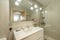 Bathroom with frameless mirror, lamps with glass shades, flower