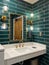 A bathroom with green subway tile walls.