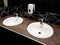 Bathroom interior in black and white. Round ceramic washbasins. Mirrors, plastic soap dish and chrome faucets for washing hands af