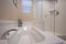 Bathroom interior of a home with shiny bathtub and glass walled shower stall