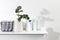 Bathroom interior. Metal basket with rolled face towels, white grooved vase with eucalyptus branch, shampoo and cream jars on