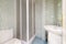 Bathroom with white porcelain sink, marble countertop, chrome taps, frameless mirror, white shower stall and tiled walls with