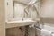 bathroom with white porcelain sink on marble countertop, cream