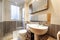 Bathroom With wooden furniture with integrated mirror hanging on the wall, smooth walls and with dark tiles on the middle of the