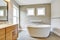 Bathroon interior with vanity cabinet, two sinks and white bath tub.