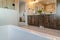 Bathtub and double sink bathroom vanity with wooden cabinets and large mirror