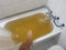 bathtub full of yellow water due to rust or impurities with human leg entering.