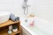 Bathtub with Plumerria Flowers and Inflatable Flamingo Toy Ring Bamboo Face Brush Gray Towel Sink Home SPA Concept Relax