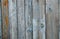 Battered, faded old vertical wooden planks with splotches of knots and remnants of light blue paint.