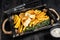 Battered Fish and chips dish with french fries and tartar sauce in a wooden tray. Black wooden background. Top view