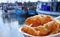 Battered fish served on a plate against fishing boats at sunset