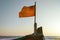 The battered flag at the bow of the boat flutters against the background of the sea and the setting sun. Sun glare and color