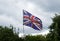 Battered union jack flag against stormy sky