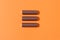 Battery in pattern on orange background. Concept charging, environmental pollution, electrical devices. Flat lay