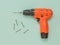 Battery-powered orange drill and self-tapping screws on a light background