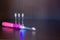 A battery-powered, pink-colored, electric pink toothbrush with three interchangeable nozzles lies on a shelf
