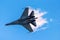 Battle fighter jet flying dives breaking clouds on a blue sky