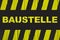 Baustelle in German, construction site warning sign with yellow and black stripes