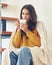 Bautiful young woman sitting onstairs in warm clothes and drinking coffee, wrapped in blanket