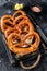 Bavarian baked Salted pretzels in a wooden tray. Black background. Top view