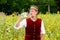 Bavarian man standing in field of sunflowers and drinking water from a bottle