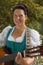 Bavarian woman in dirndl smiling while playing guitar at the lake