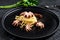 Bavette pasta with baby octopus. Black background. Top view