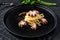 Bavette pasta with baby octopus. Black background. Top view