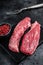 Bavette raw beef meat steak or Sirloin flap on marble board. Black background. Top view