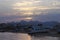 Bay and abandoned beach. Old destroyed boat on the shore. Sun peeks out from behind the clouds before sunset. Low mountains in the