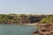 Bay of blue ocean on the background of a rocky coast with a grotto and green vegetation