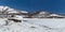 The bay is covered with ice near snow-covered hills in winter on a sunny day