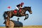 Bay horse stretching over a barrel jump at horse show