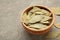 Bay leaves in wooden bawl on a concrete background