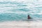 BAYAHIBE, DOMINICAN REPUBLIC - MAY 21, 2017: Black boy bathes in the water on the beach. Copy space for text.