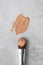 BB cream or foundation smear and makeup brush on luxury marble background, top view. Swatch of professional cosmetic creamy liquid