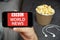 BBC World News on the screen of mobile phone with popcorn and earphones on the background, Close u mans hand holding a