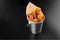 BBQ cheese fried stripes in a metal bucket onblack background with sauce fryed