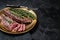BBQ grilled Bavette Bavet beef meat steak with herbs on a plate. Black background. Top view. Copy space