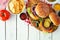 BBQ hamburgers with potato chips, overhead view table scene on white wood