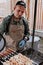 BBQ party in the backyard. A man in a baseball cap and apron prepares a chicken shish kebab for a large group of friends. Turkish